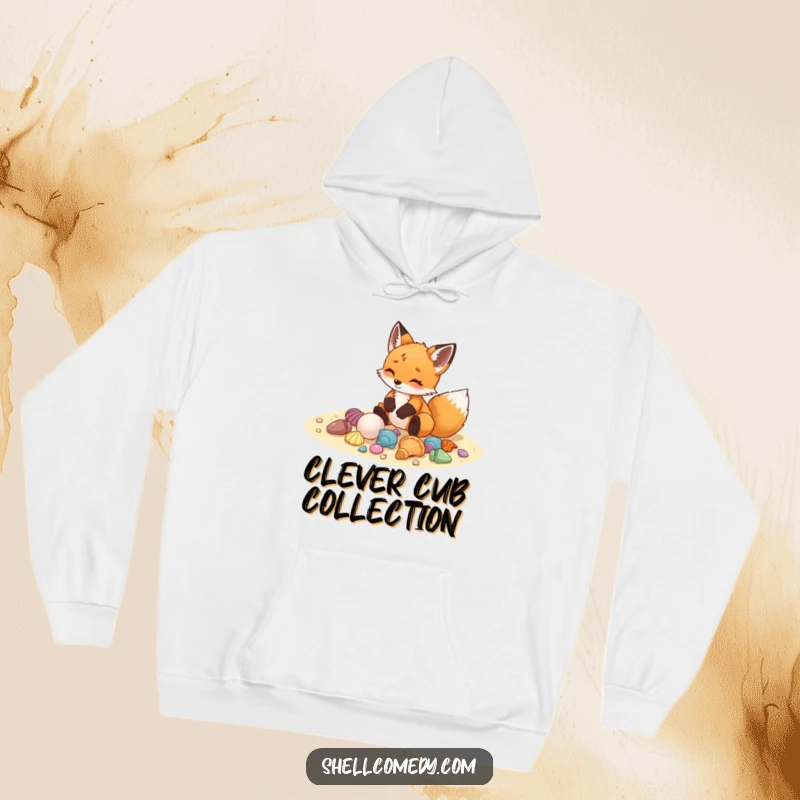Funny fox cub hoodie arranging colorful seashells on sand with delight, cozy beach apparel.